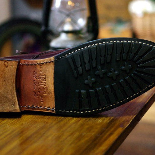 Close-up of a shoe sole with a brand logo on a wooden surface