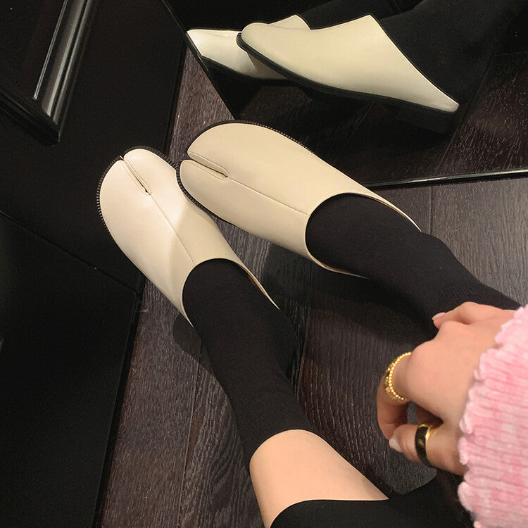 White loafers worn with black pants on a wooden floor.