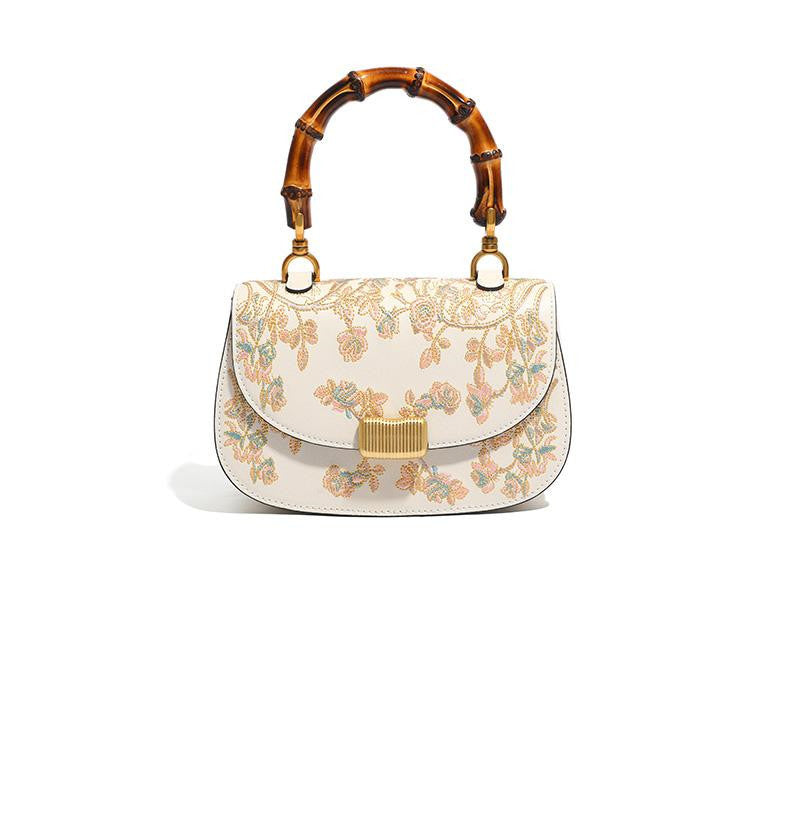 Floral embroidered handbag with bamboo handle on a white background