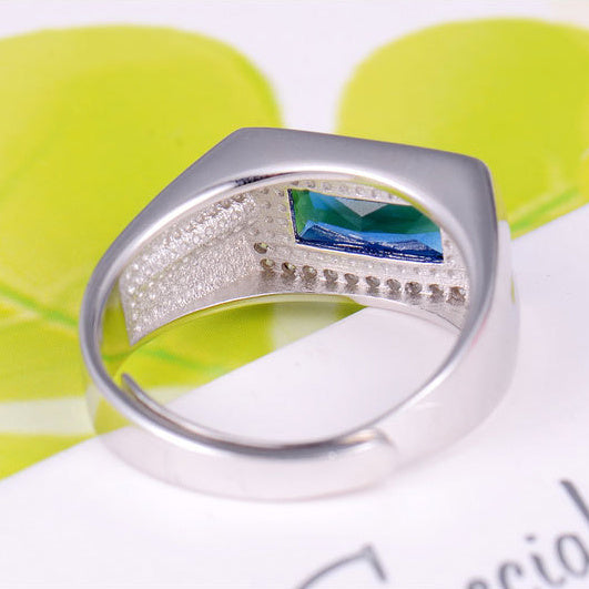Silver ring with a colorful gemstone on a white and green background