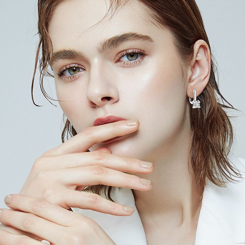 Close-up of a woman wearing earrings with a plain background