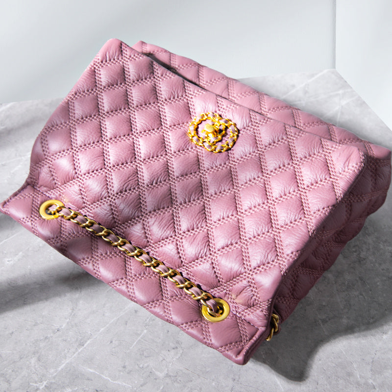 Pink quilted handbag with gold chain and clasp on a light gray background
