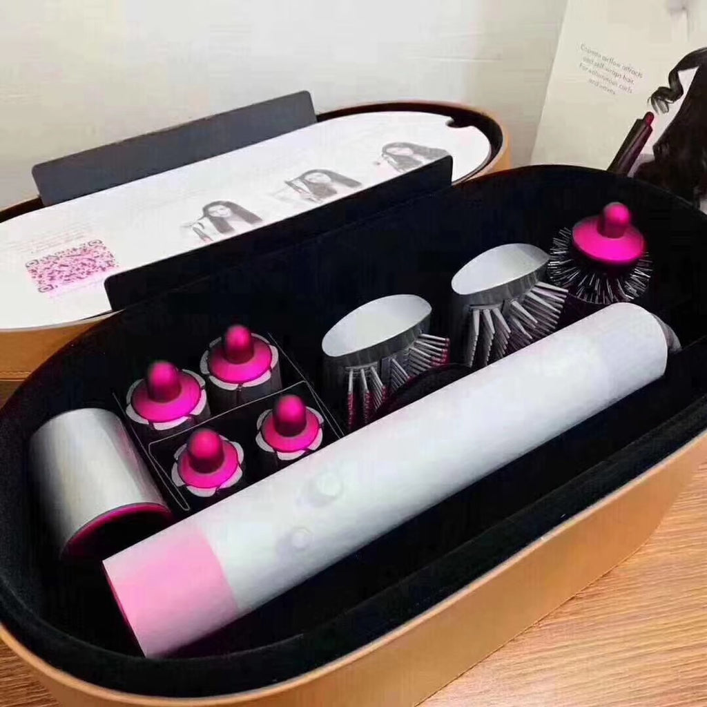 Hair curling iron set with pink accents in a black case on a wooden surface.