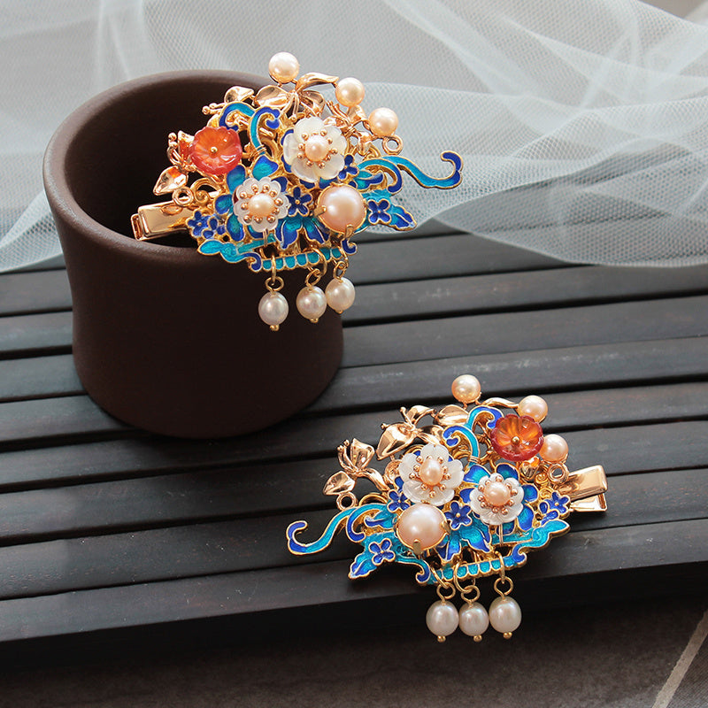 Decorative hair clips with floral designs and pearls on a wooden surface.