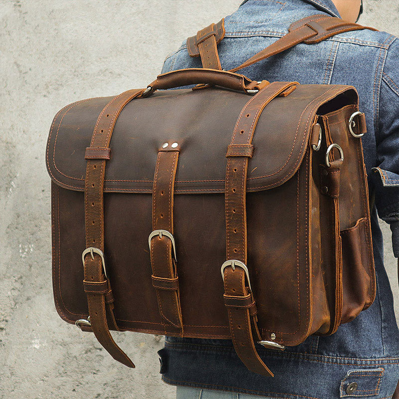 Brown leather satchel backpack worn by a person with a denim jacket.