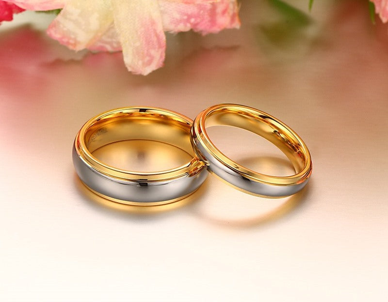 Two gold rings on a soft pink background with flowers.