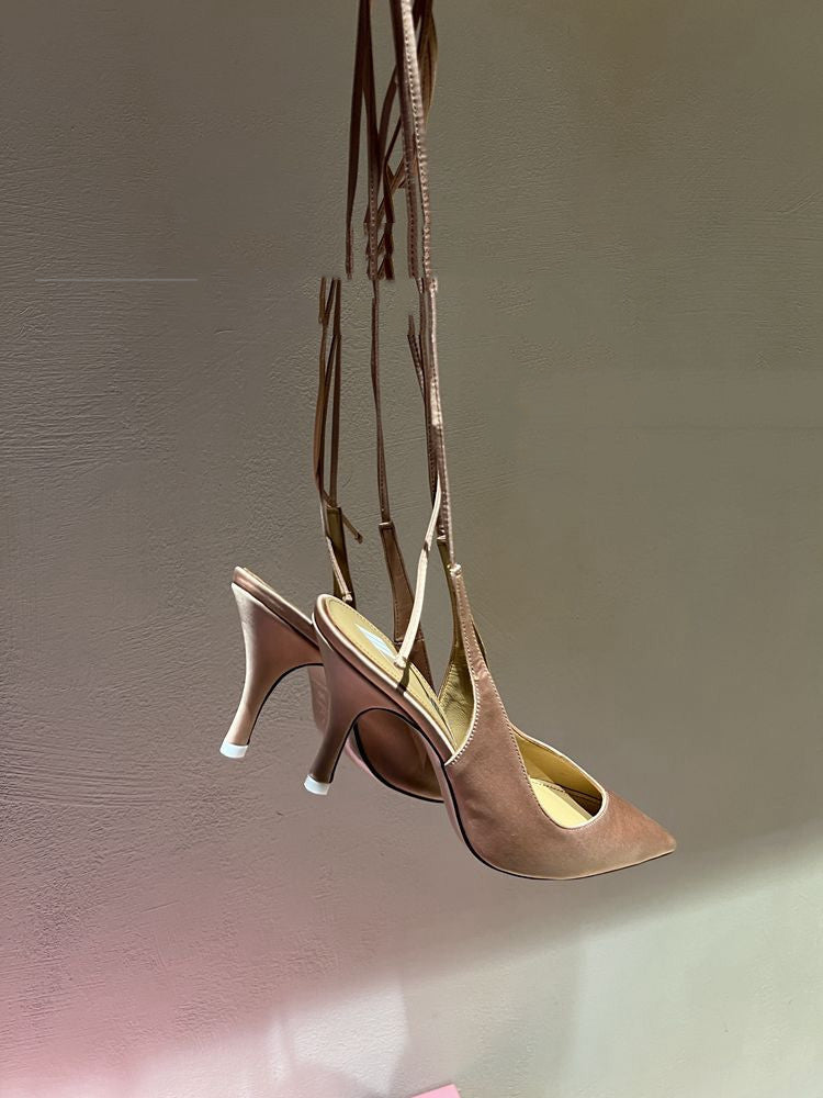 Pair of high-heeled shoes hanging against a plain background