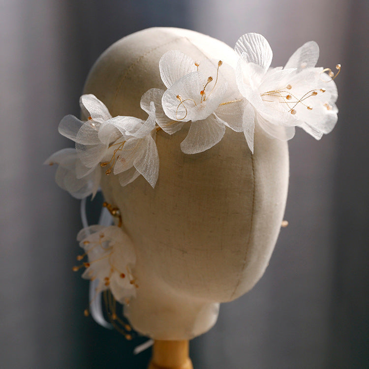 White floral headpiece on a mannequin head against a dark background