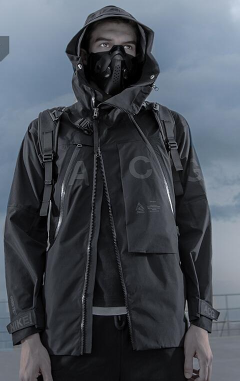 Person wearing a dark raincoat with a hood and backpack against a cloudy sky.
