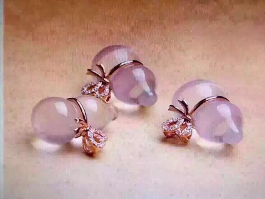 Pair of pink teardrop earrings with rose gold accents on a beige background