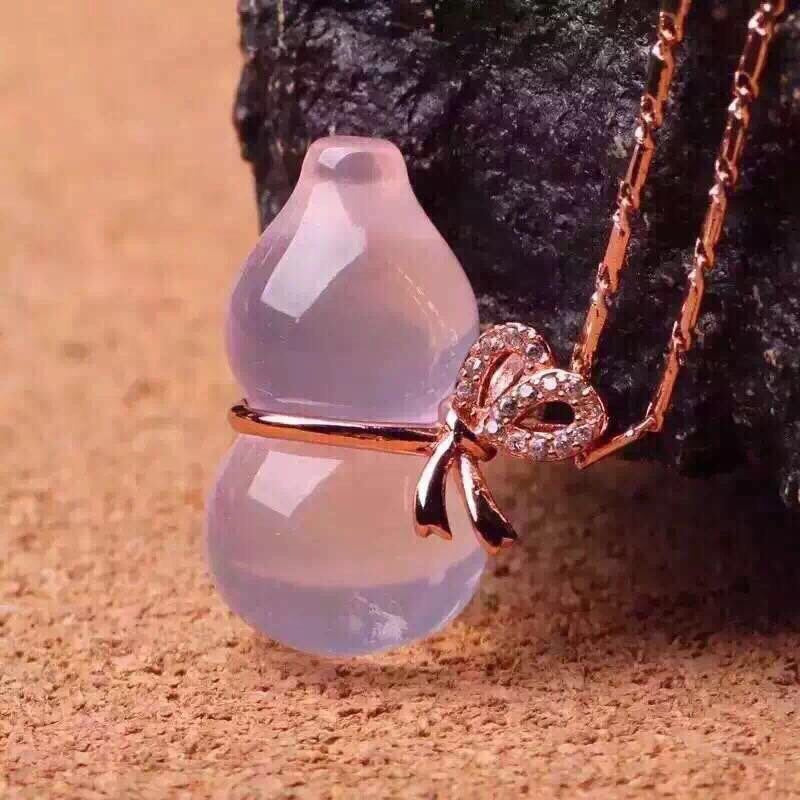 Necklace with a pink stone and rose gold bow pendant on a textured surface