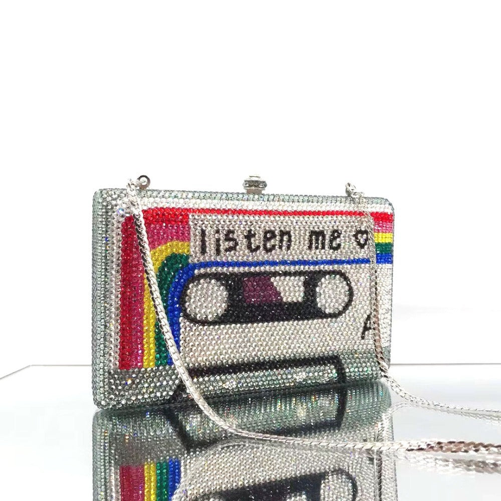 Sparkly clutch bag designed like a cassette tape with 'Listen Me' text and rainbow colors on a white background.