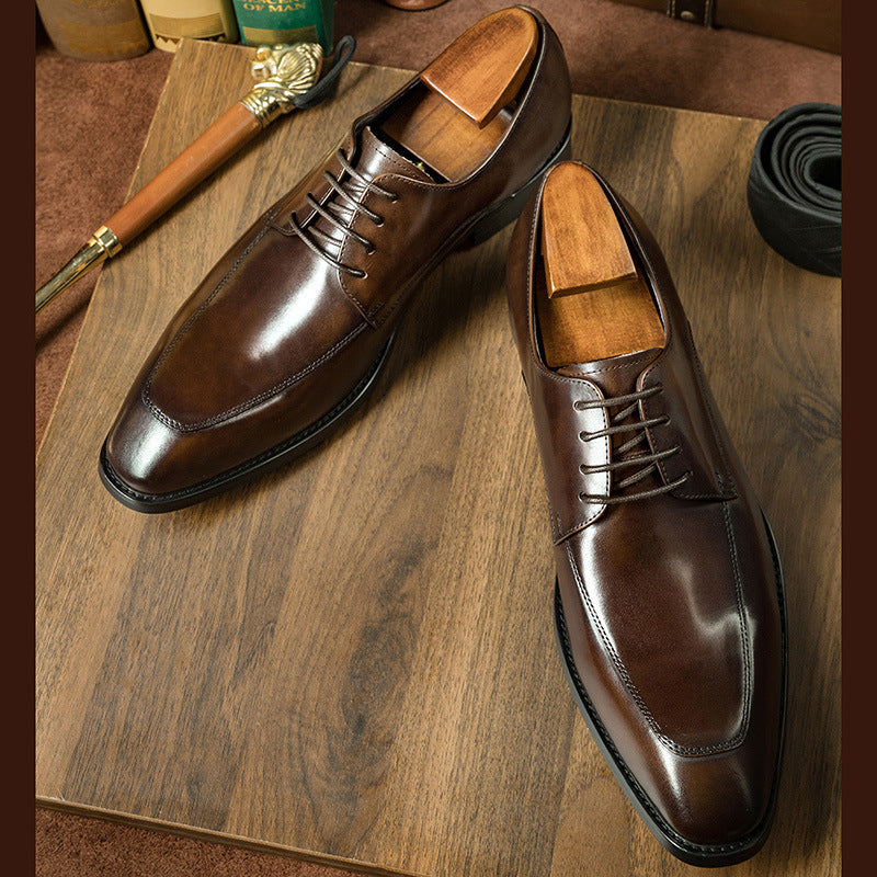 Pair of brown dress shoes on a wooden surface with a brush and other items.