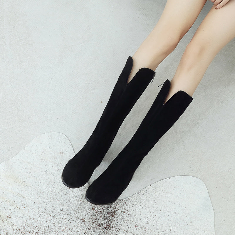 Black knee-high boots worn by a person on a light gray background