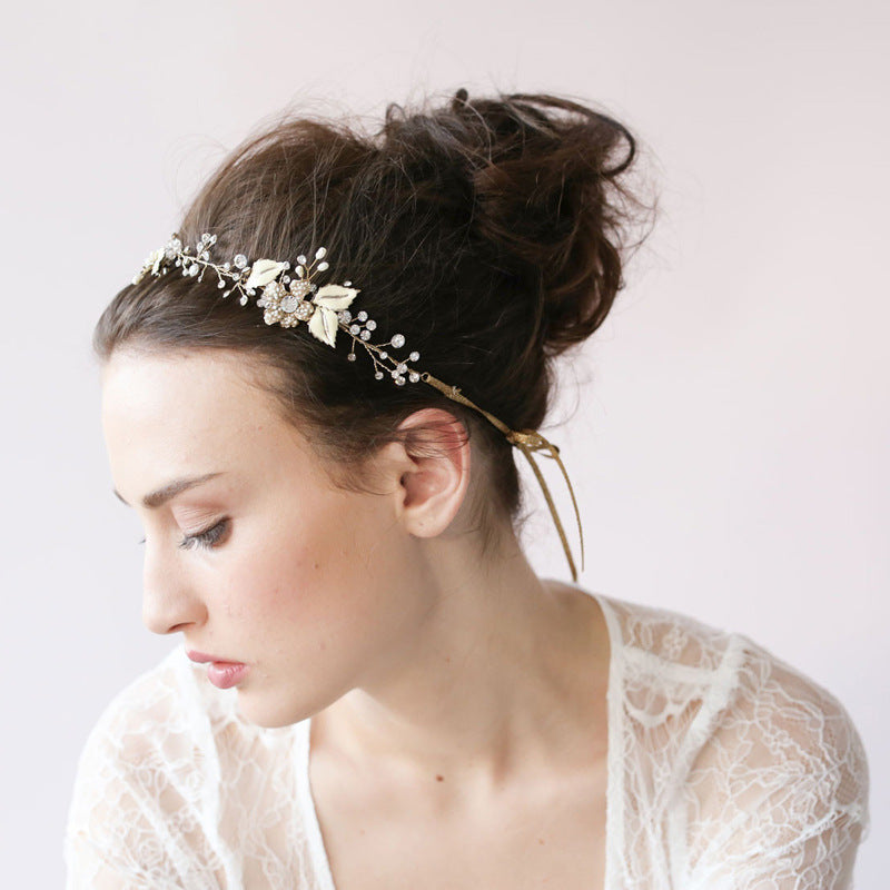 Woman wearing a floral headband with a white lace top against a light background