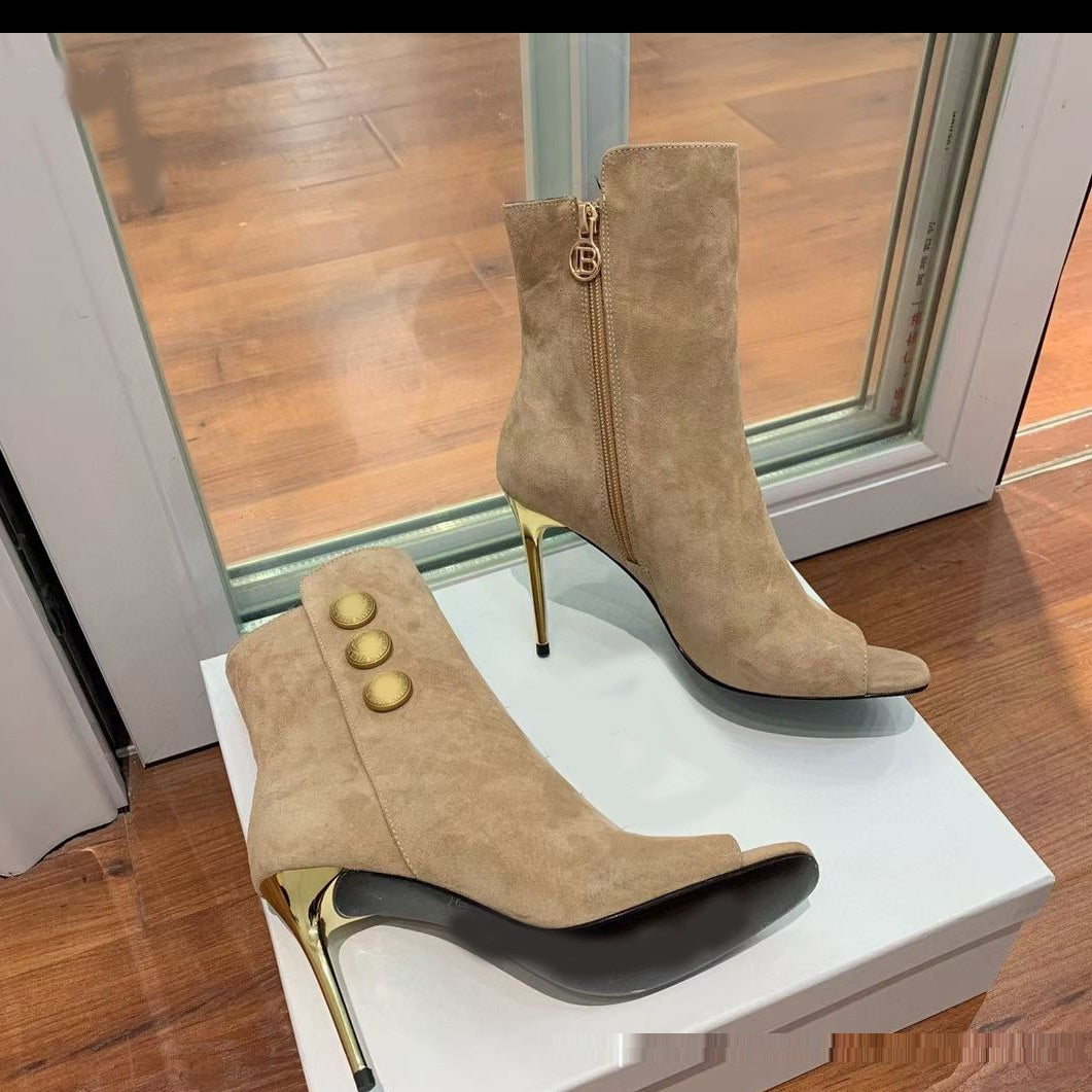 Pair of beige high-heeled boots with gold accents on a white surface.