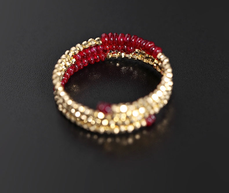 Gold and red beaded ring on a black background