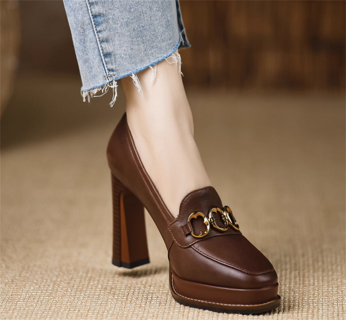 Brown high-heeled shoe with gold buckle on a blurred background
