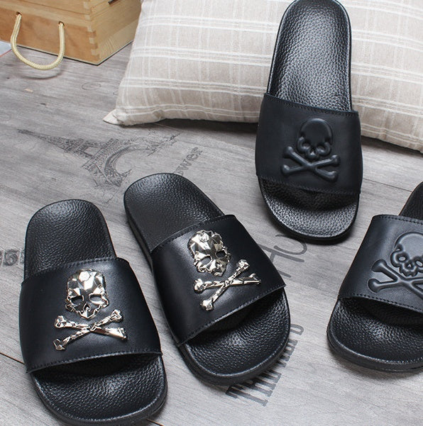 Black slides with skull design on a wooden floor