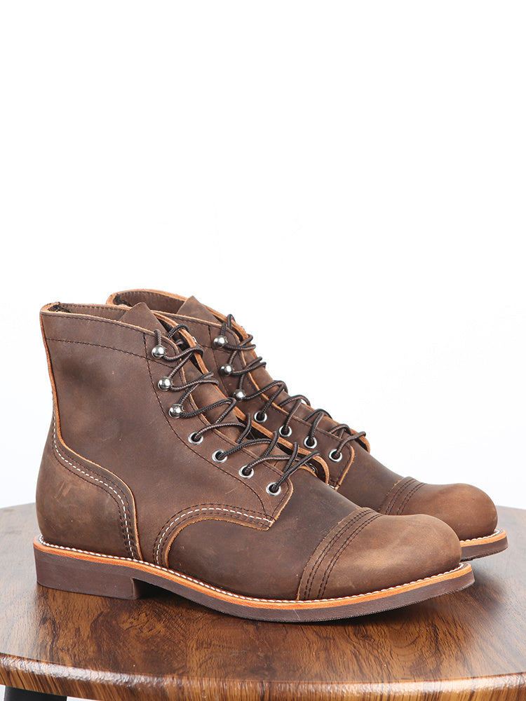 Pair of brown leather boots on a wooden surface with a white background