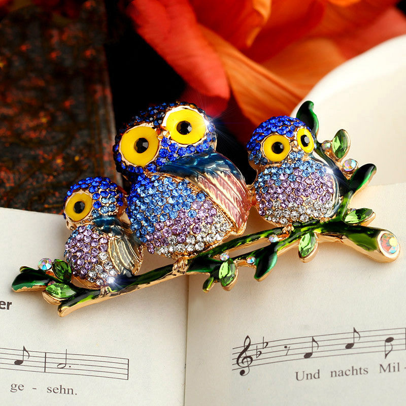 Colorful owl brooches on a branch with a blurred background