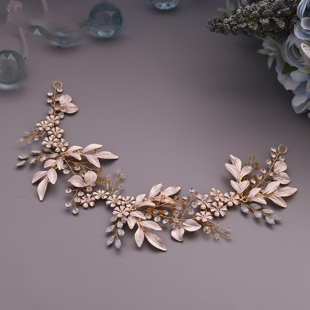 Decorative floral hairpiece with leaves and crystals on a gray background