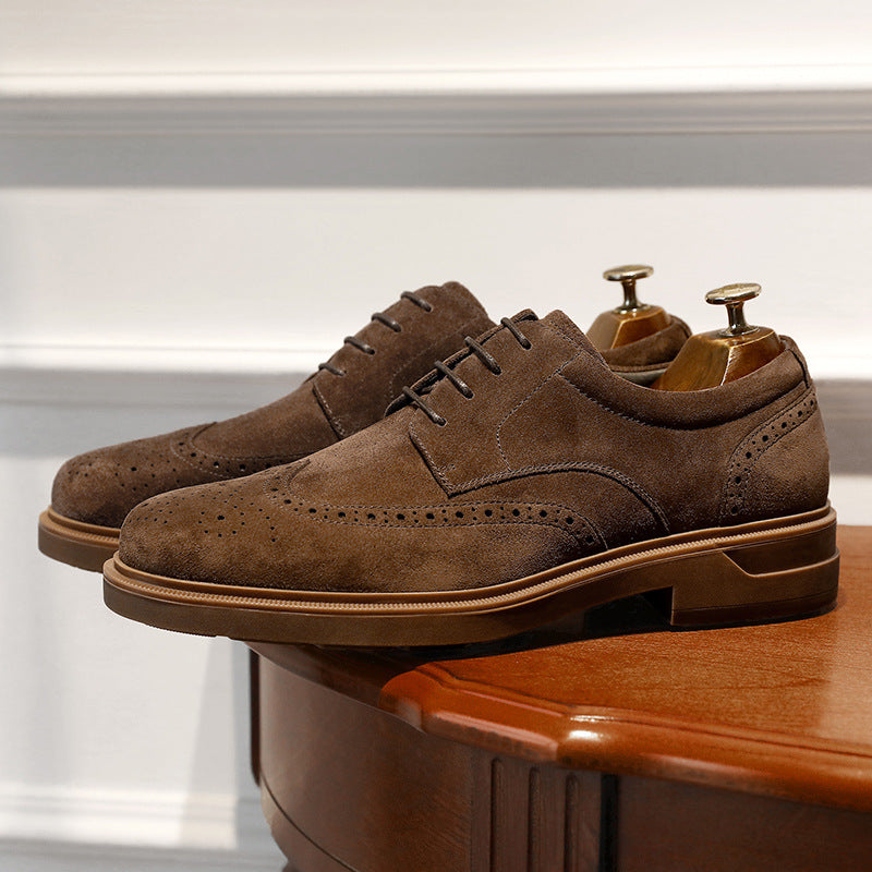 Brown suede dress shoes on a wooden surface with a white background