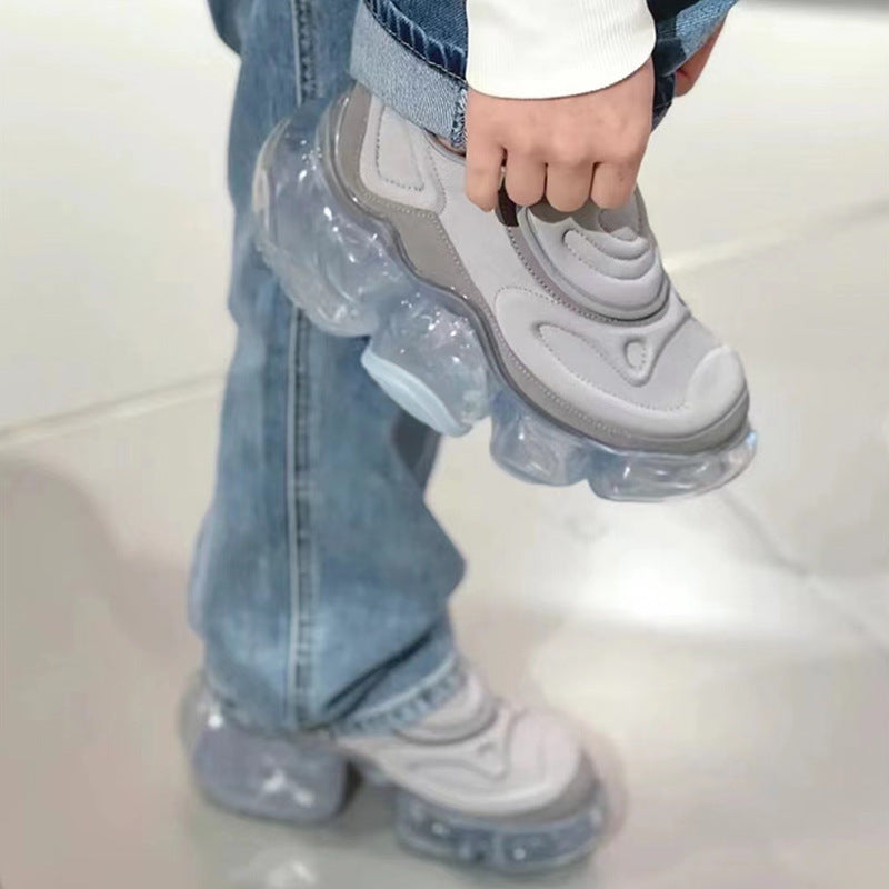 Person wearing transparent plastic shoes over sneakers on a light background