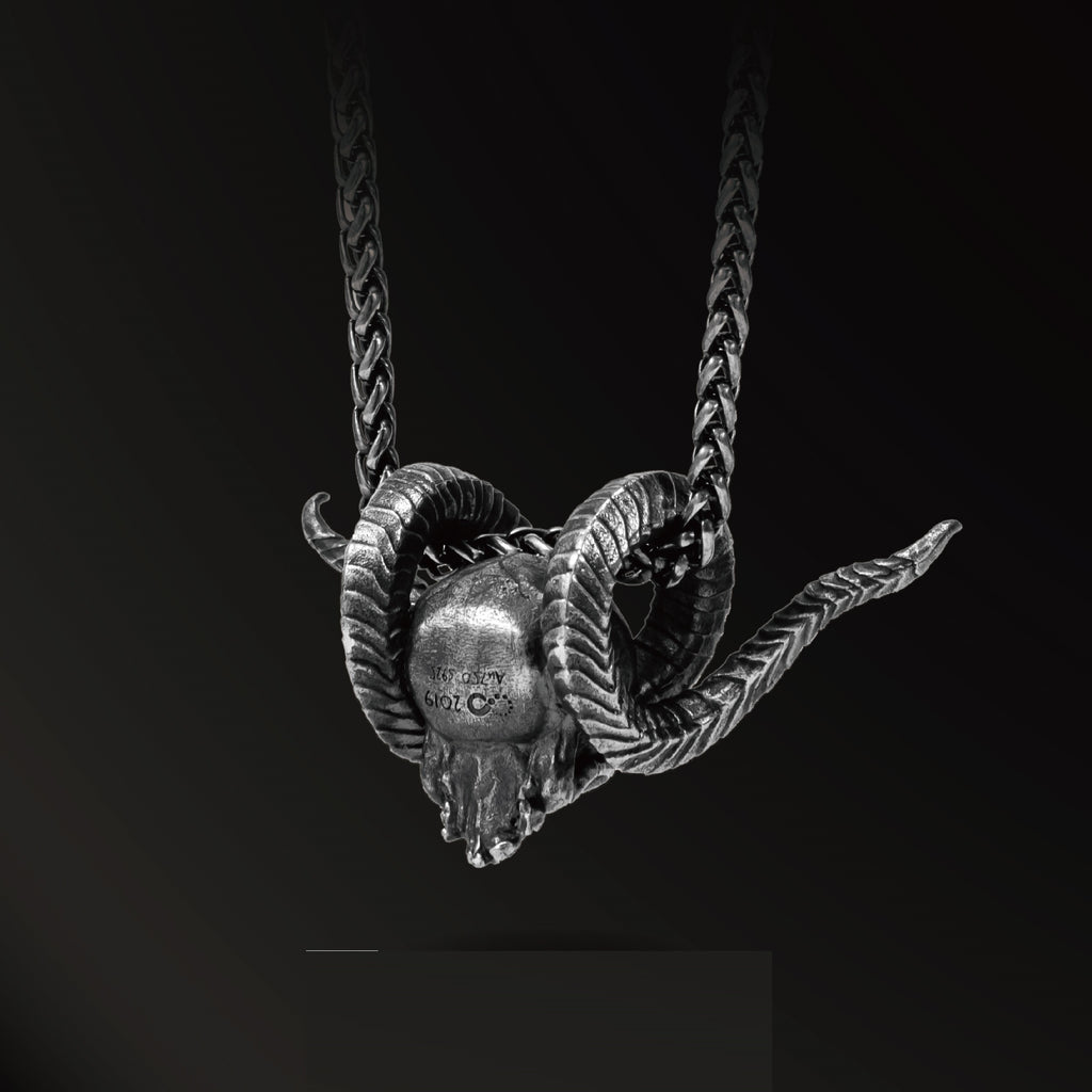 Silver ram skull necklace on a black background