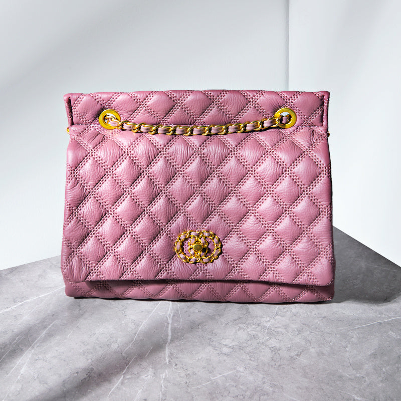 Pink quilted handbag with gold chain and clasp on a light gray background