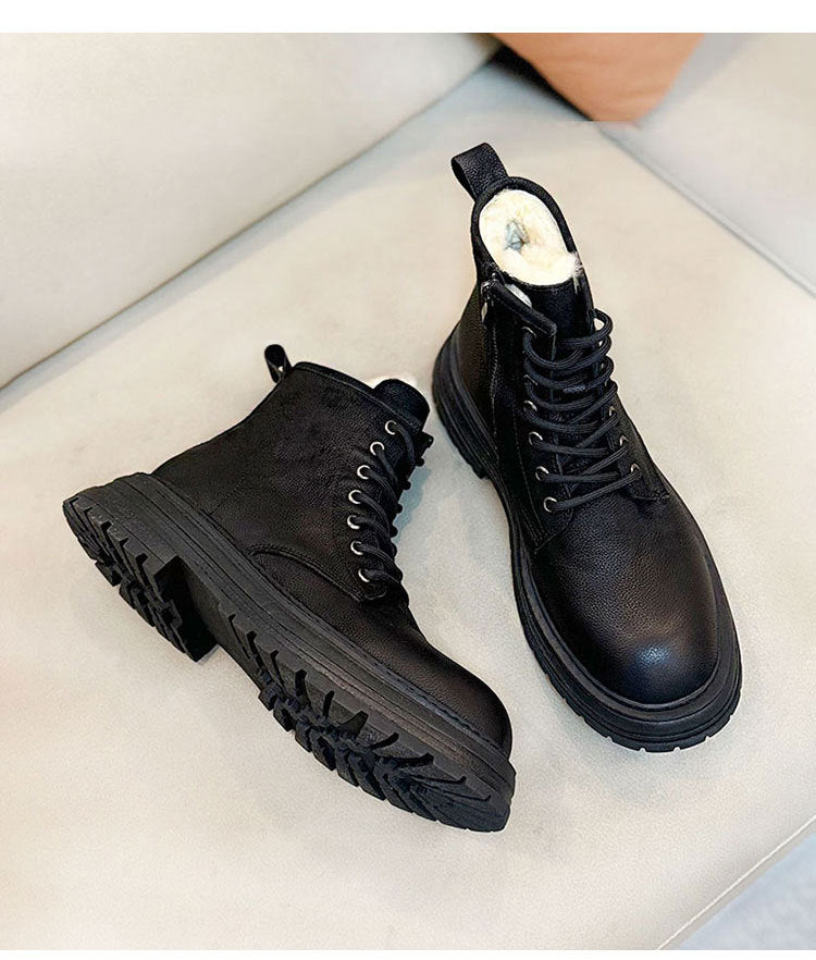 Pair of black leather boots on a light gray surface
