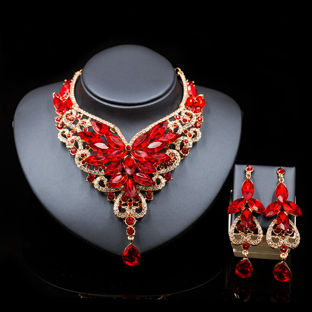 Red and gold jewelry set with necklace and earrings on a black background