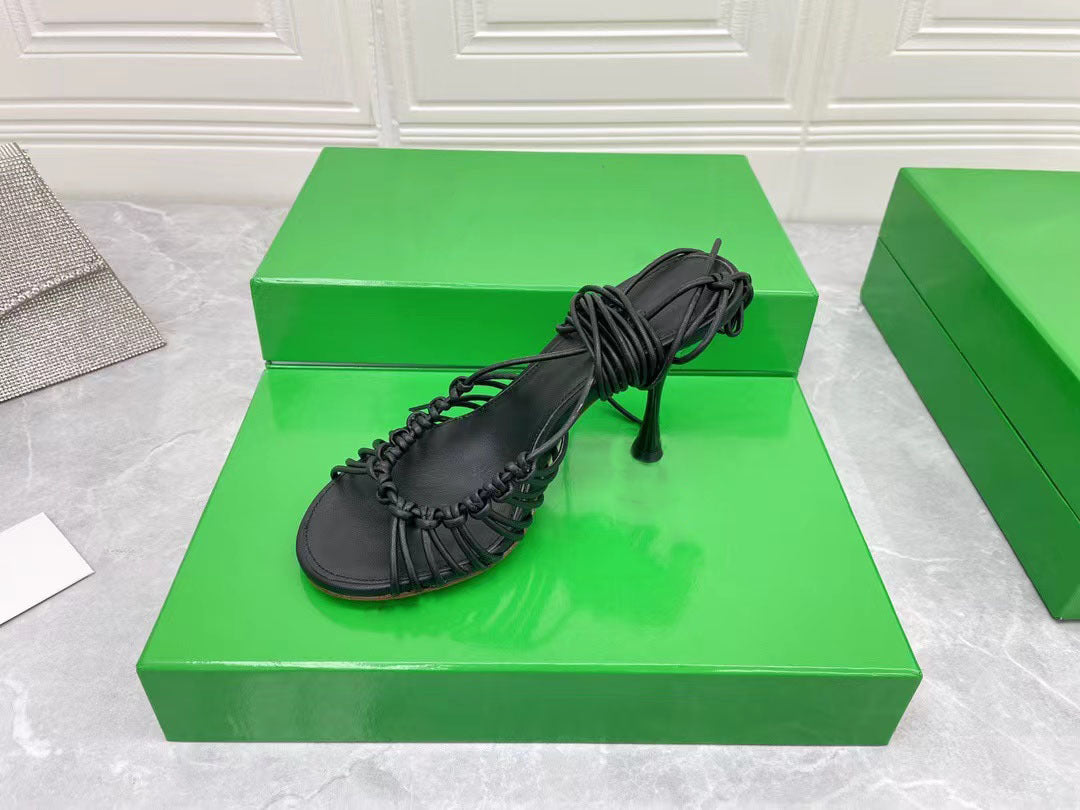 Black sandal on a green box with a white textured background