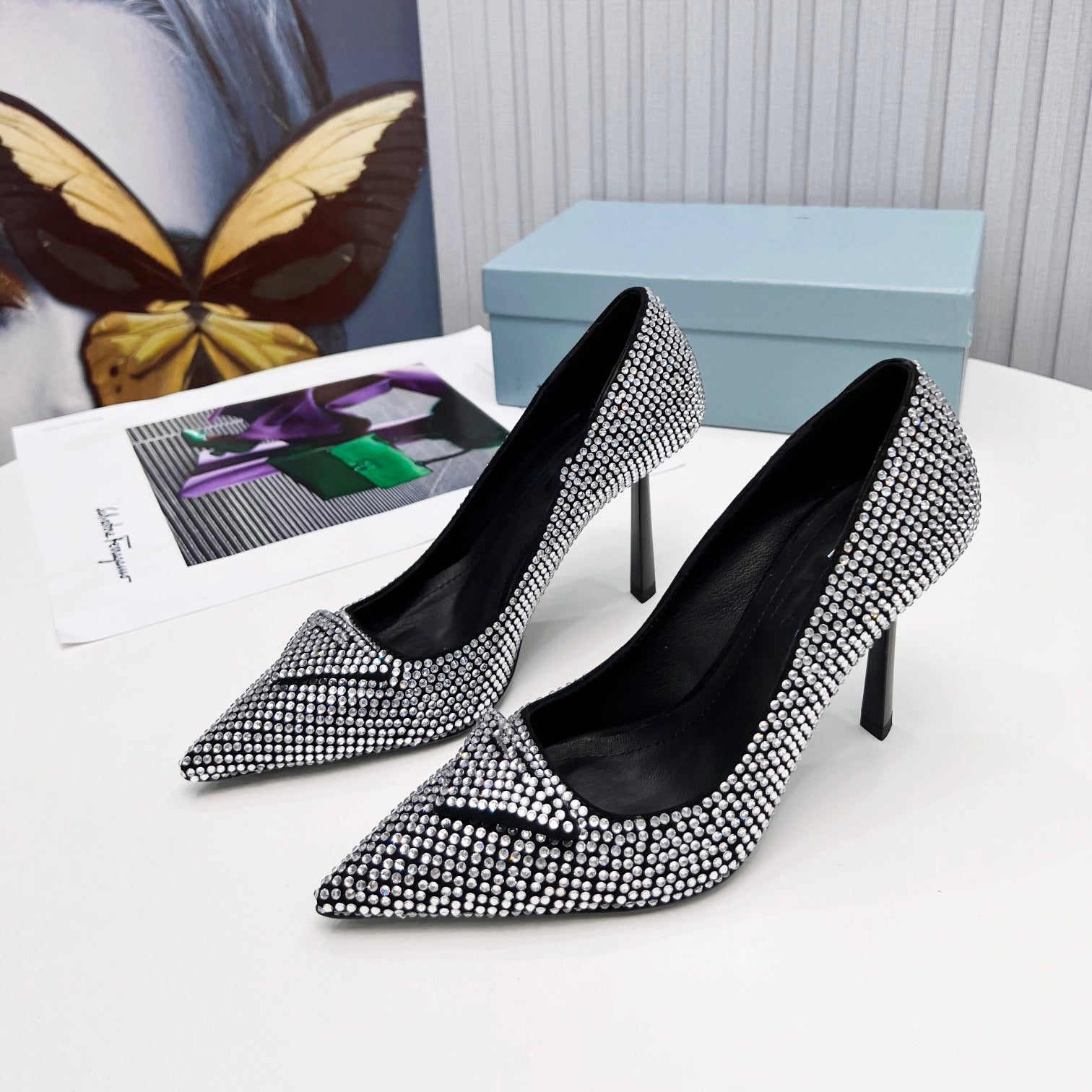 Black high-heeled shoes with silver studded details on a white surface.