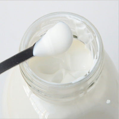 Jar of yogurt with a spoon inside on a white background