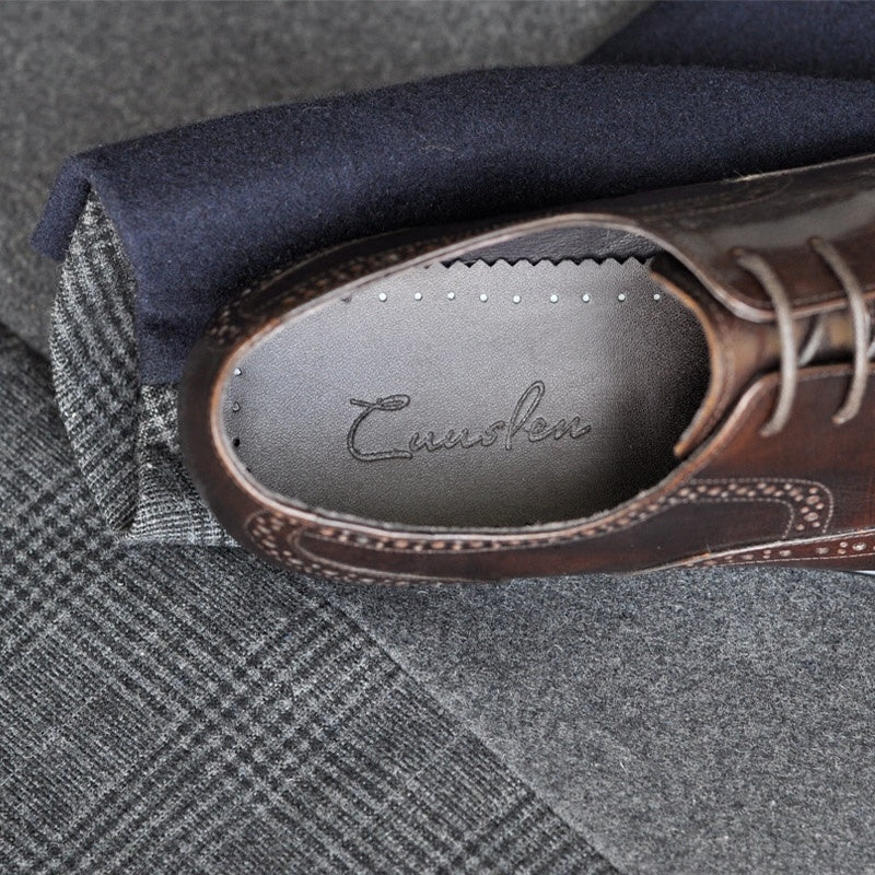 Brown leather shoe with 'Cushion' branding on a gray fabric background