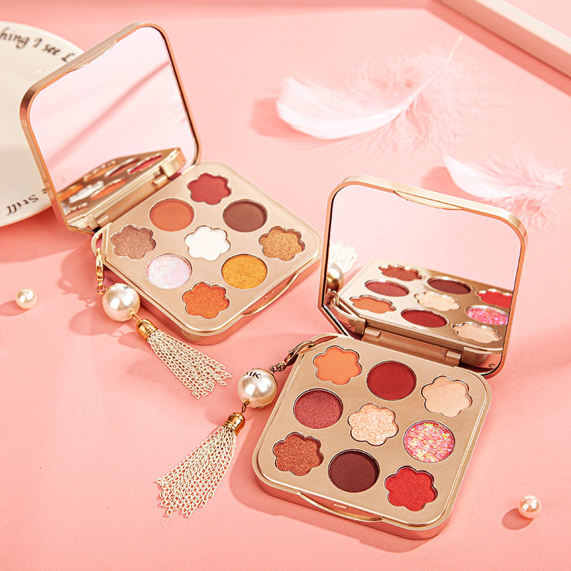 Two open makeup palettes with colorful shades on a pink background