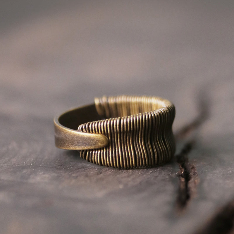 Bronze ring with textured design on a dark surface
