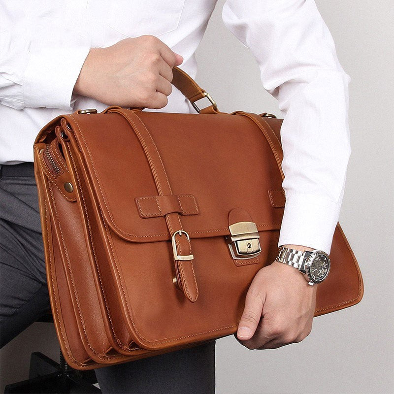 Person holding a brown leather briefcase with a plain background
