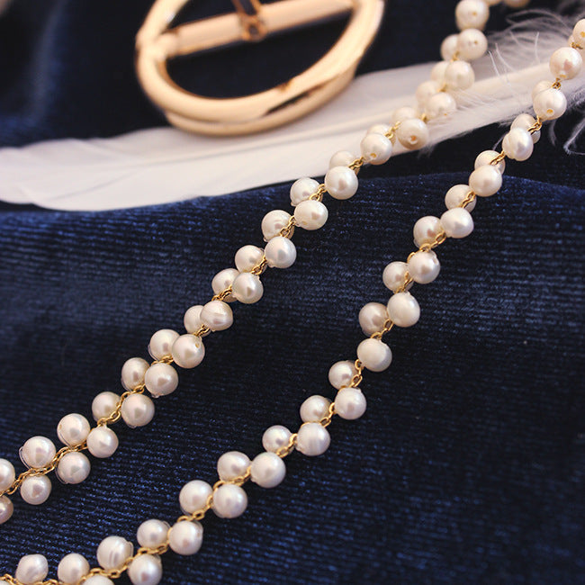 Pearl necklace with gold chain on a dark blue fabric background