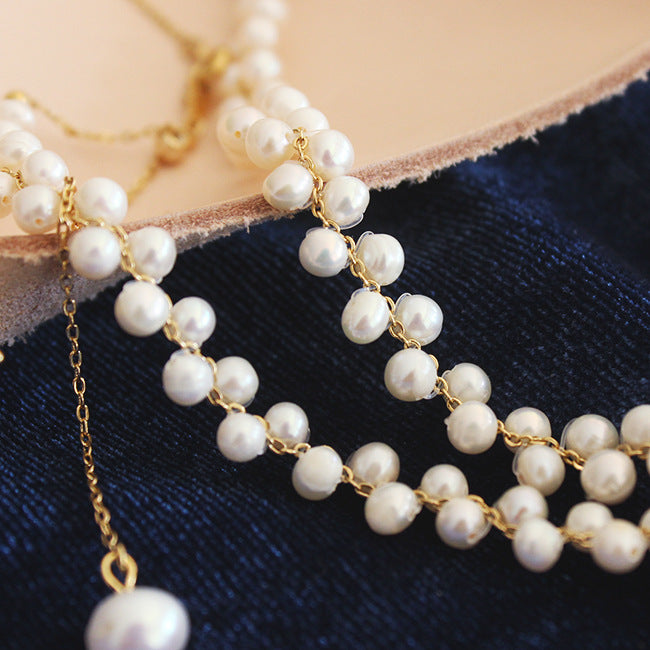 Pearl necklace with gold chain on a blue fabric background