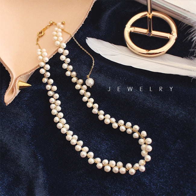 Pearl necklace draped over a shoe with a gold ring and feather on a dark blue background, labeled 'Jewelry'.
