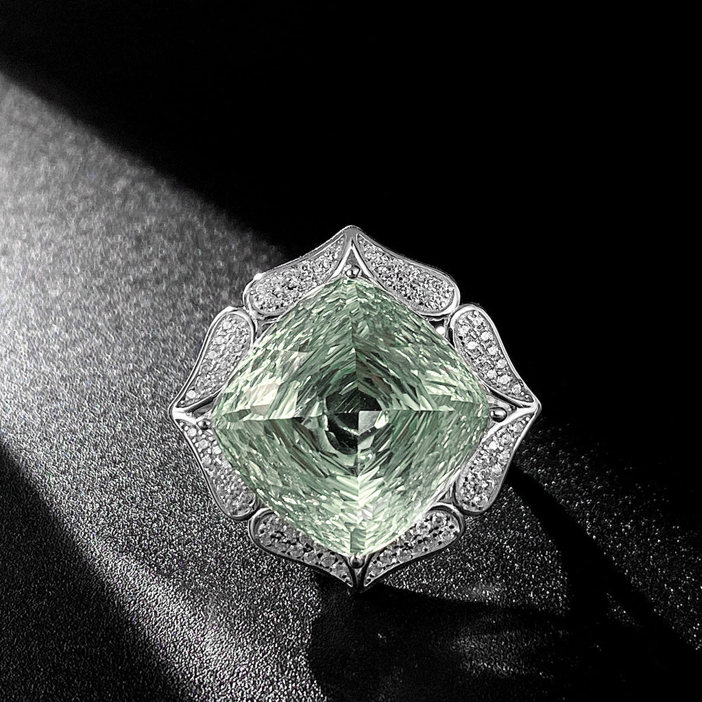 Green diamond ring with silver decorative band on a black background