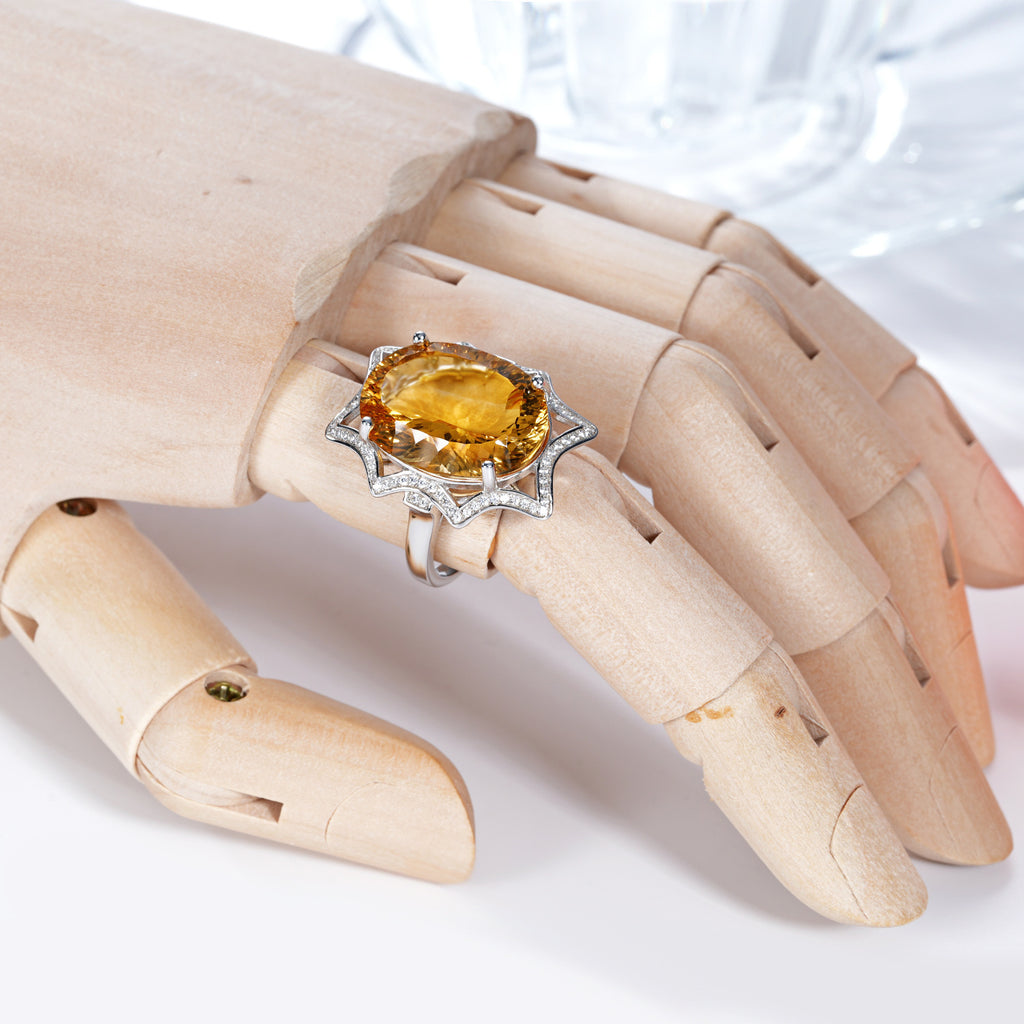 Ring with a yellow gemstone on a wooden hand model