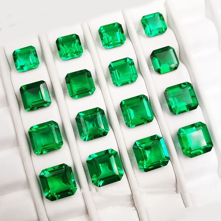 Multiple green emerald stones arranged in a grid on a white background