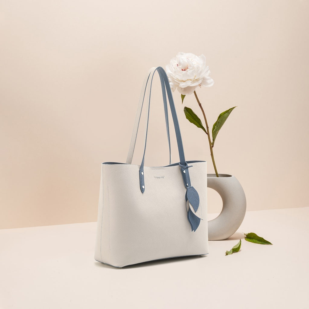 White handbag with blue accents on a beige background