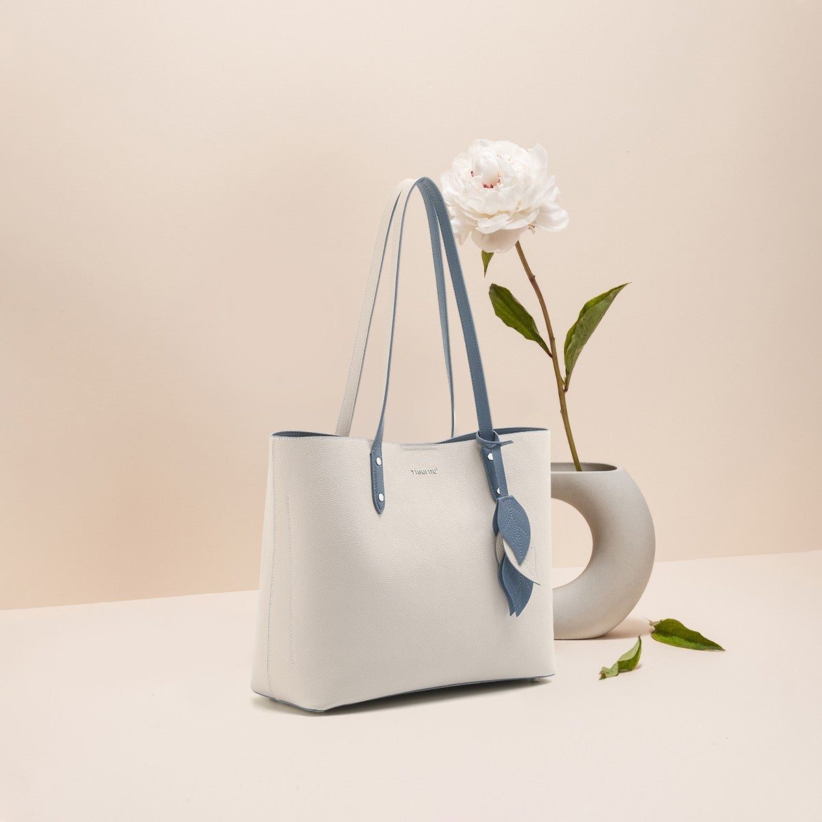 White handbag with blue accents on a beige background