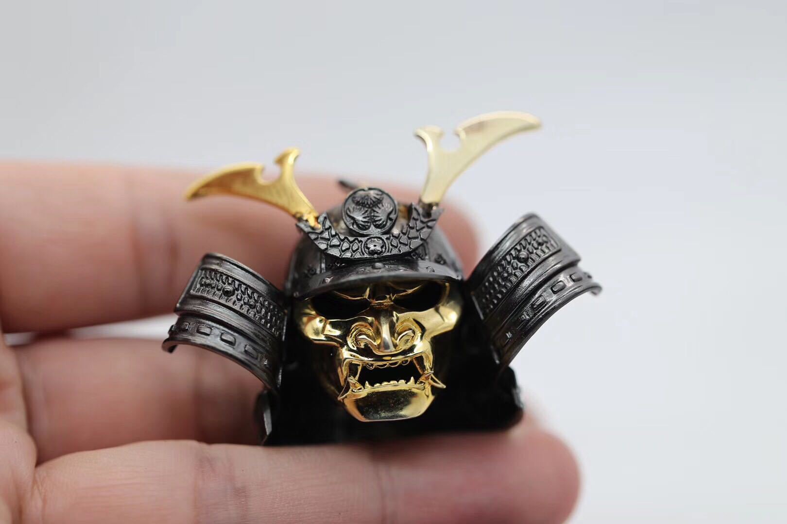 Metallic skull pendant with gold accents held in a hand against a light background