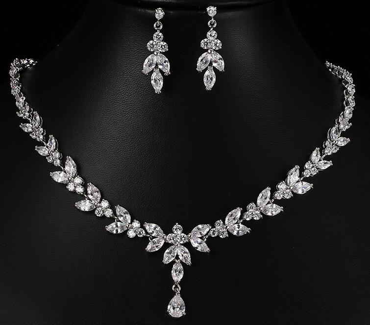 Silver necklace and earrings set on a black background