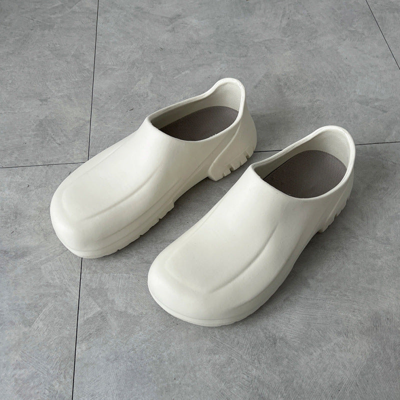 Pair of white clogs on a gray tiled floor